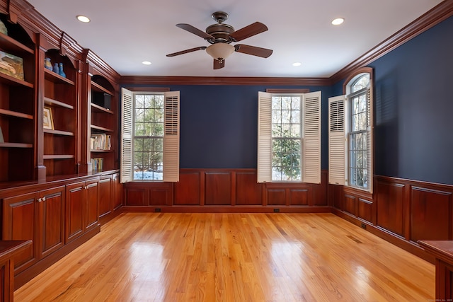 empty room featuring light wood-type flooring, a wainscoted wall, and plenty of natural light