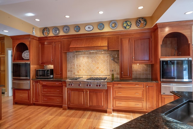 kitchen with stainless steel appliances, light wood-type flooring, brown cabinetry, and a warming drawer