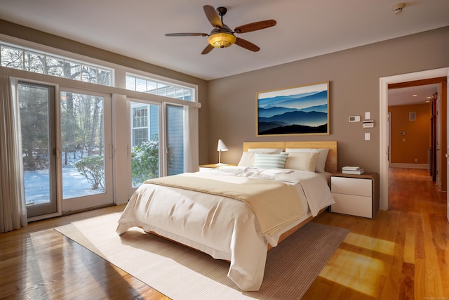 bedroom featuring access to exterior, light wood-style floors, baseboards, and ceiling fan