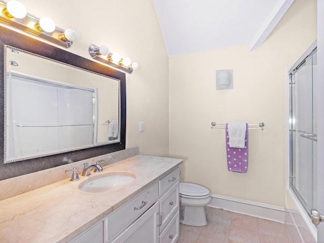 bathroom with lofted ceiling, toilet, vanity, baseboards, and tile patterned floors