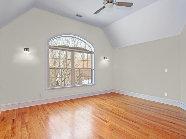 empty room with light wood-type flooring, lofted ceiling, visible vents, and baseboards