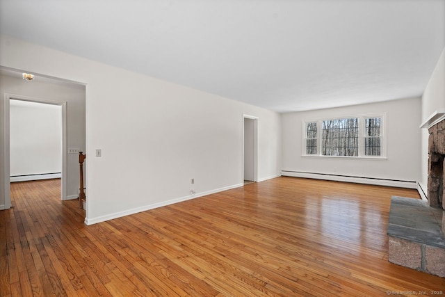 unfurnished living room featuring baseboards, a fireplace with raised hearth, a baseboard radiator, hardwood / wood-style floors, and a baseboard heating unit