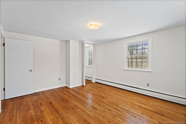 unfurnished bedroom featuring hardwood / wood-style flooring, baseboards, multiple windows, and a baseboard heating unit