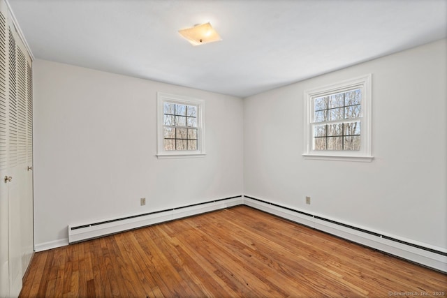 unfurnished bedroom featuring a baseboard radiator, a closet, baseboard heating, and wood finished floors