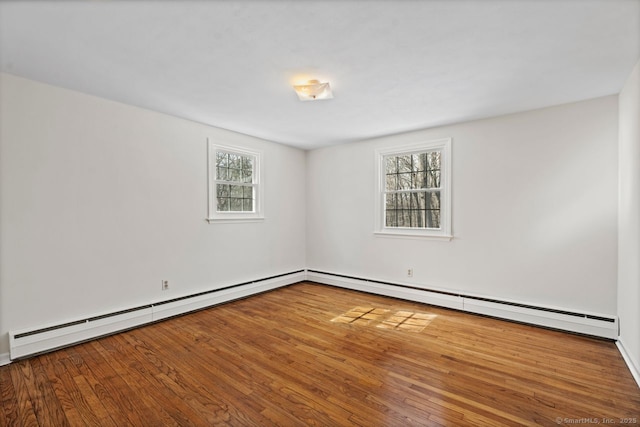 spare room with a baseboard heating unit, baseboard heating, and wood finished floors