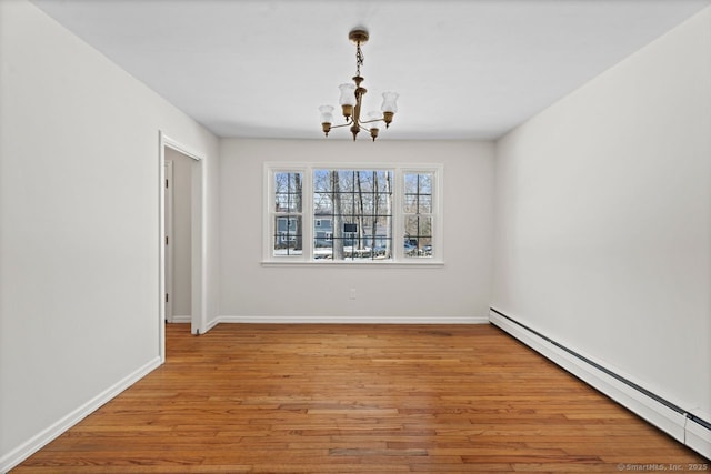 empty room featuring light wood-type flooring, a baseboard radiator, a chandelier, and baseboards