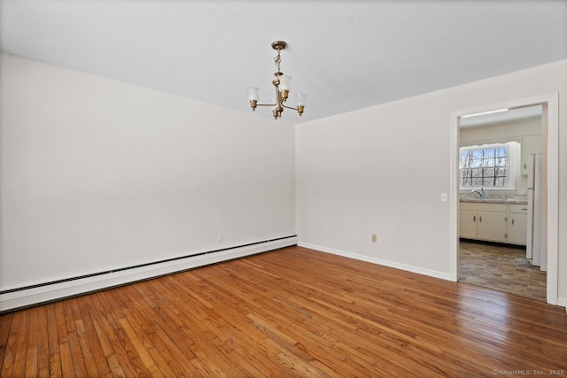 unfurnished room featuring baseboards, baseboard heating, light wood-style floors, a chandelier, and a sink