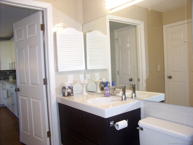 bathroom with tile walls, toilet, vanity, and decorative backsplash