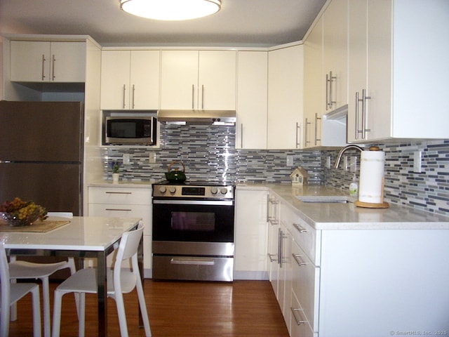 kitchen featuring tasteful backsplash, light countertops, appliances with stainless steel finishes, a sink, and under cabinet range hood