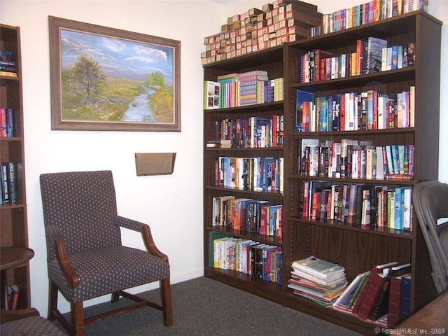 living area featuring carpet floors, wall of books, and baseboards