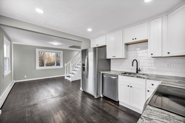 kitchen featuring baseboard heating, decorative backsplash, stainless steel appliances, and a sink