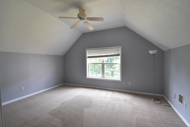 bonus room with carpet floors, lofted ceiling, a ceiling fan, a textured ceiling, and baseboards