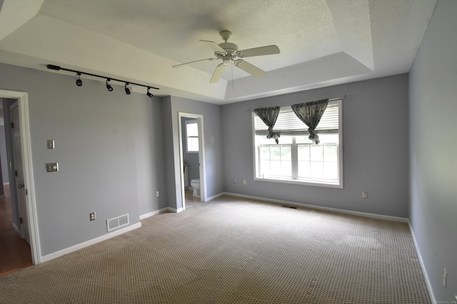 unfurnished room featuring a textured ceiling, a tray ceiling, visible vents, and baseboards