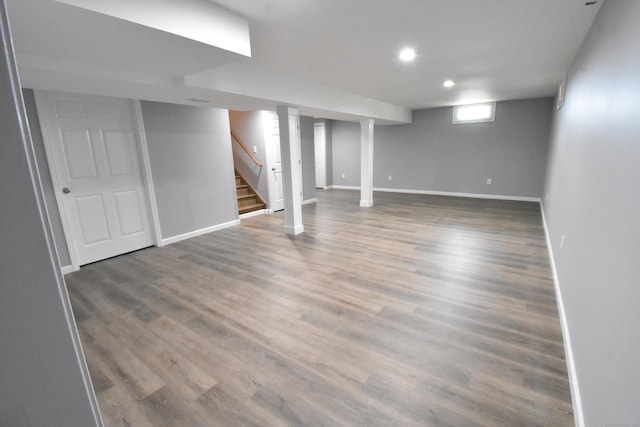 below grade area with stairs, recessed lighting, wood finished floors, and baseboards