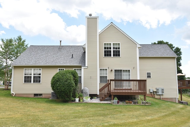 rear view of house with a yard, a shingled roof, a chimney, and a wooden deck