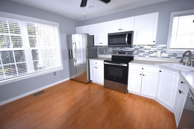 kitchen featuring stainless steel appliances, light countertops, visible vents, white cabinets, and a sink