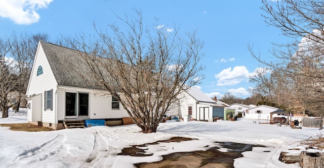 snow covered property featuring entry steps and roof with shingles