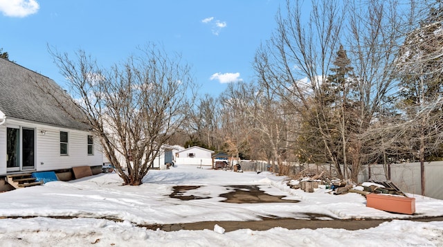 snowy yard featuring entry steps and fence