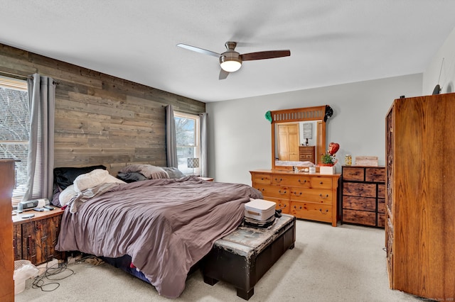 bedroom with ceiling fan, wood walls, and light colored carpet