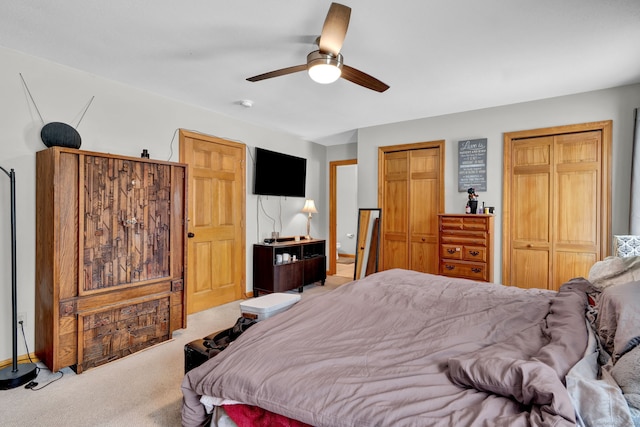 bedroom with ceiling fan, carpet, and two closets