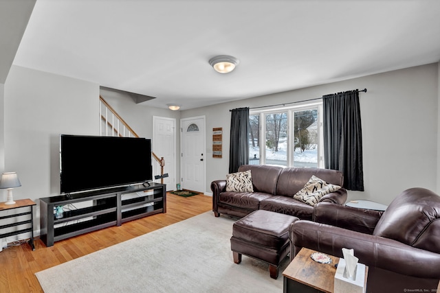 living area featuring stairs, baseboards, and wood finished floors