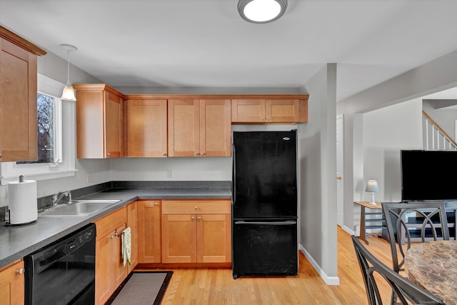 kitchen featuring black appliances, light wood-type flooring, dark countertops, and a sink