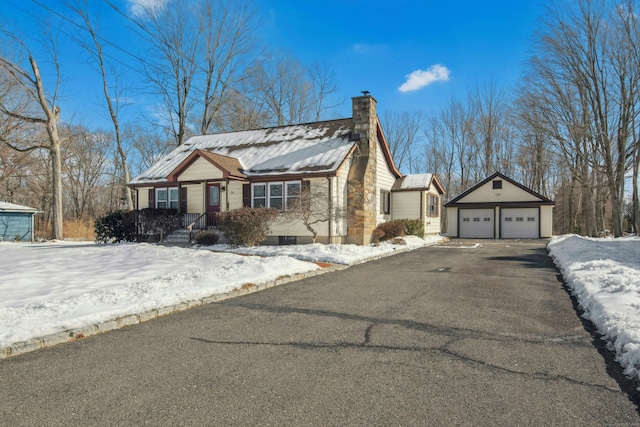 view of front of home featuring a garage, a chimney, and an outbuilding