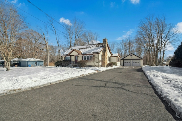 view of front facade featuring a garage, an outbuilding, and a chimney