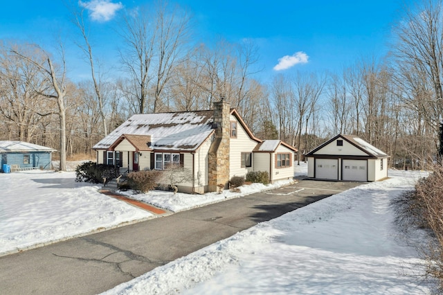 view of front of property featuring a chimney, a detached garage, and an outdoor structure