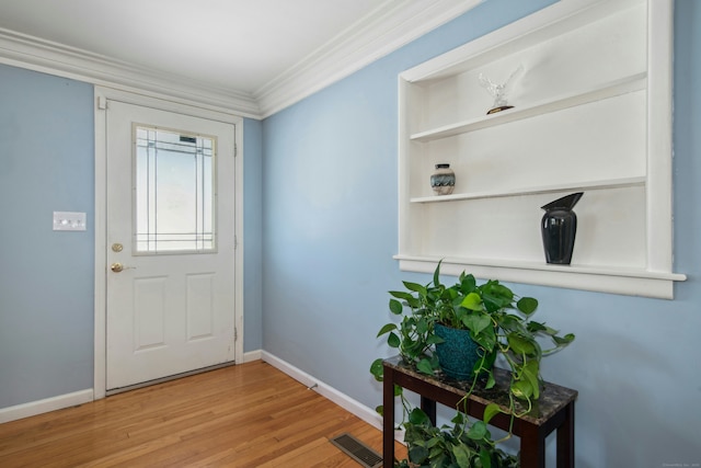 entryway with baseboards, visible vents, wood finished floors, and ornamental molding