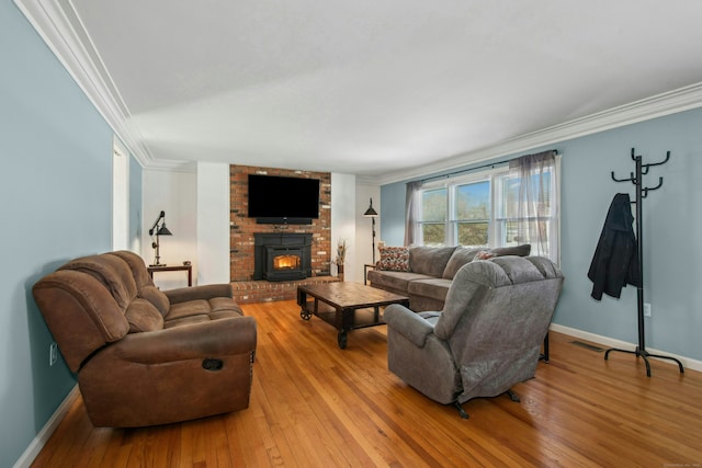 living area featuring a fireplace, baseboards, crown molding, and hardwood / wood-style floors