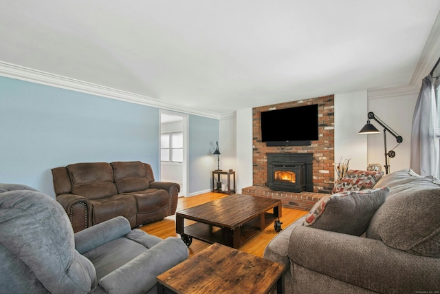 living room featuring light wood-style floors, a brick fireplace, baseboards, and crown molding