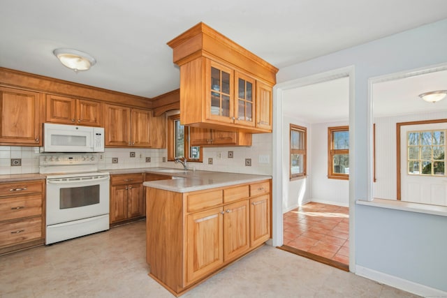 kitchen with light countertops, white appliances, a peninsula, and glass insert cabinets