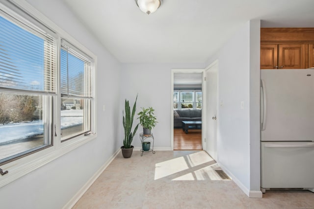 corridor with light tile patterned floors, visible vents, and baseboards