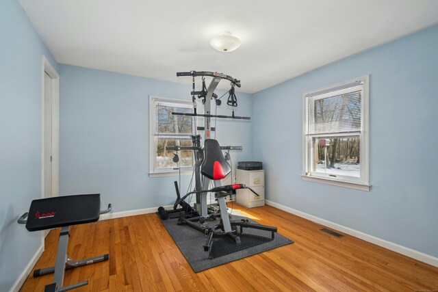 workout room with wood finished floors, visible vents, and baseboards