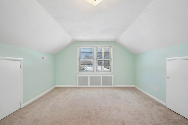 additional living space featuring visible vents, baseboards, radiator heating unit, vaulted ceiling, and carpet floors