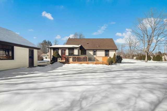 snow covered rear of property with a wooden deck