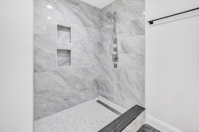 bathroom with baseboards and tiled shower