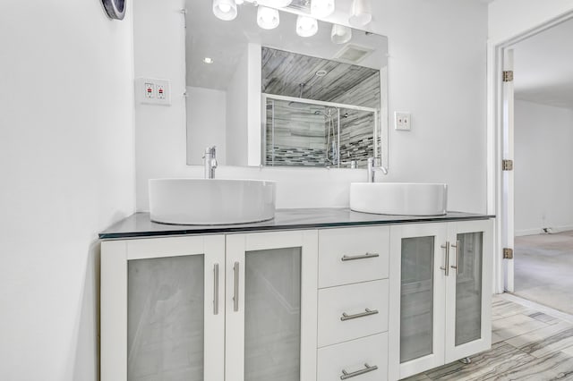 bathroom featuring double vanity, a sink, and a shower stall