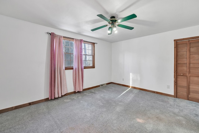 carpeted empty room featuring baseboards, visible vents, and ceiling fan