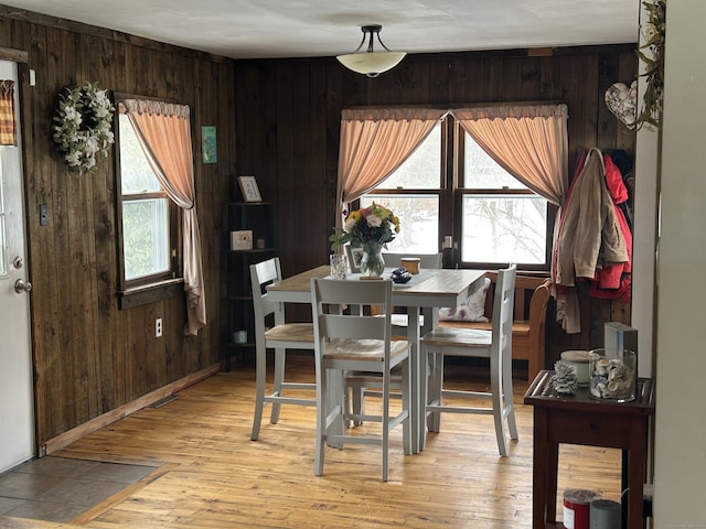 dining room with plenty of natural light, wood walls, and light wood finished floors