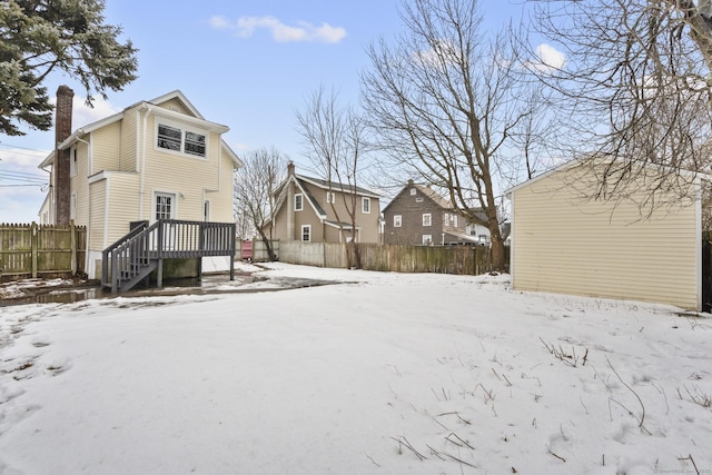 snow covered property with a chimney, fence, and a deck