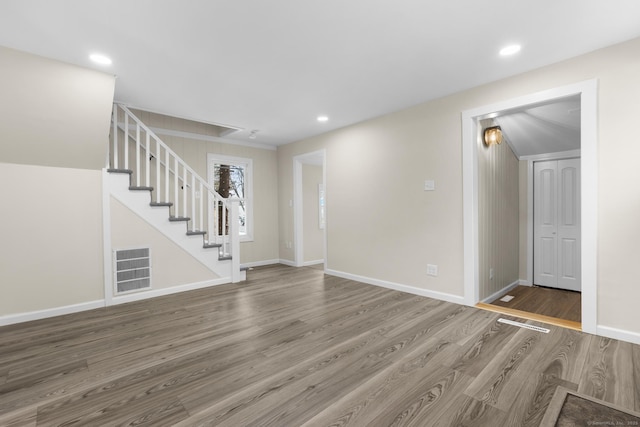 spare room featuring baseboards, visible vents, stairway, wood finished floors, and recessed lighting