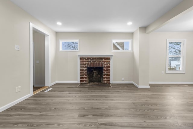 unfurnished living room with a fireplace, baseboards, and wood finished floors