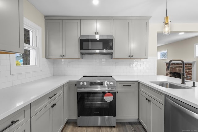 kitchen featuring gray cabinetry, stainless steel appliances, a sink, and light countertops