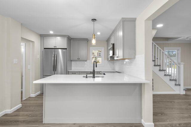 kitchen featuring dark wood-style floors, stainless steel appliances, gray cabinets, light countertops, and a sink