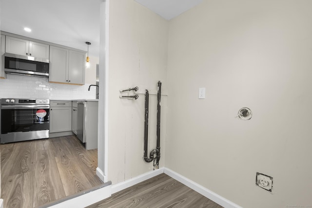 kitchen featuring stainless steel appliances, gray cabinets, light countertops, and decorative light fixtures