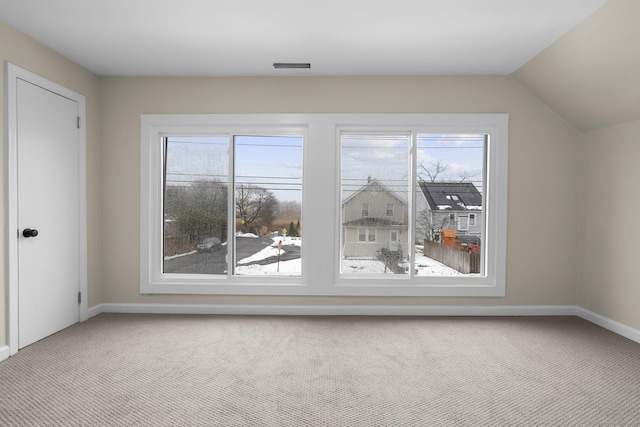 additional living space with light carpet, vaulted ceiling, and baseboards