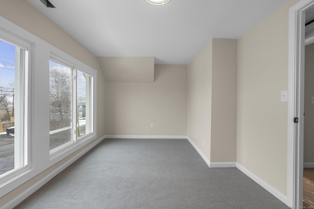 unfurnished room with baseboards, dark carpet, and vaulted ceiling