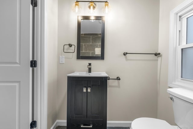 bathroom featuring toilet, baseboards, and vanity